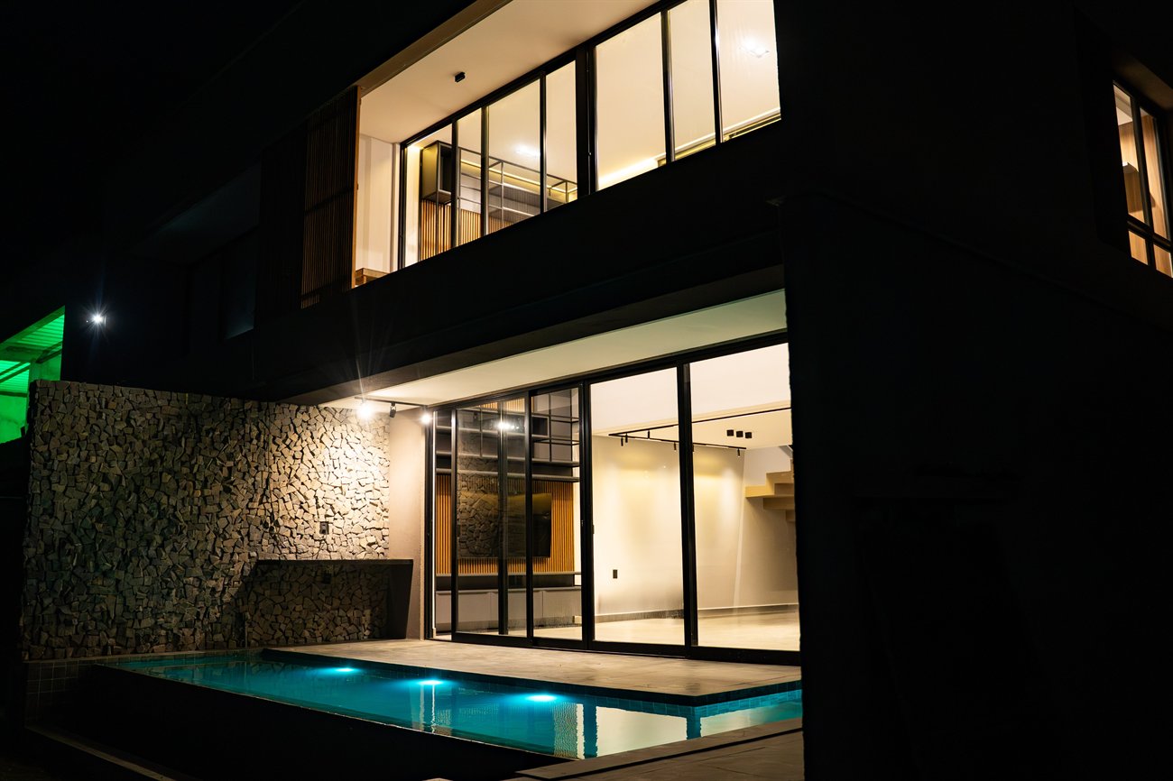 Casa do Green View iluminada à noite, com piscina.